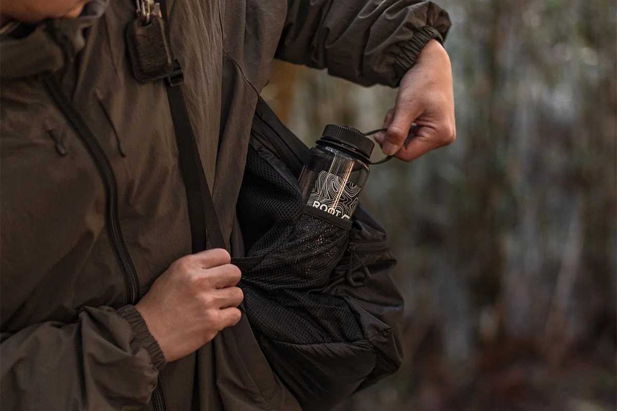 バックパックのサイドポケットから水筒を取り出す手