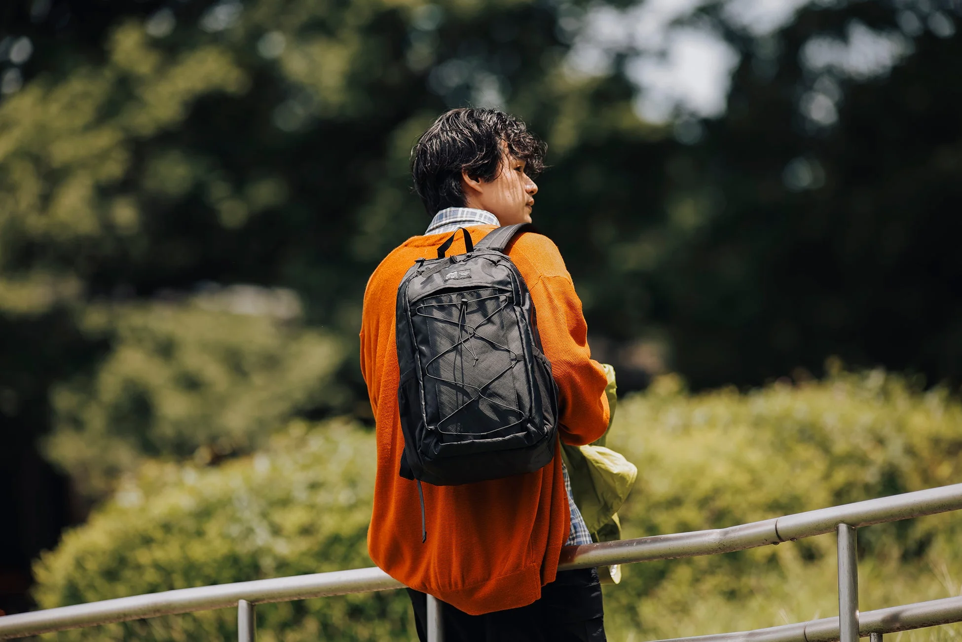 オレンジセーターと黒いバックパックの男性の後ろ姿