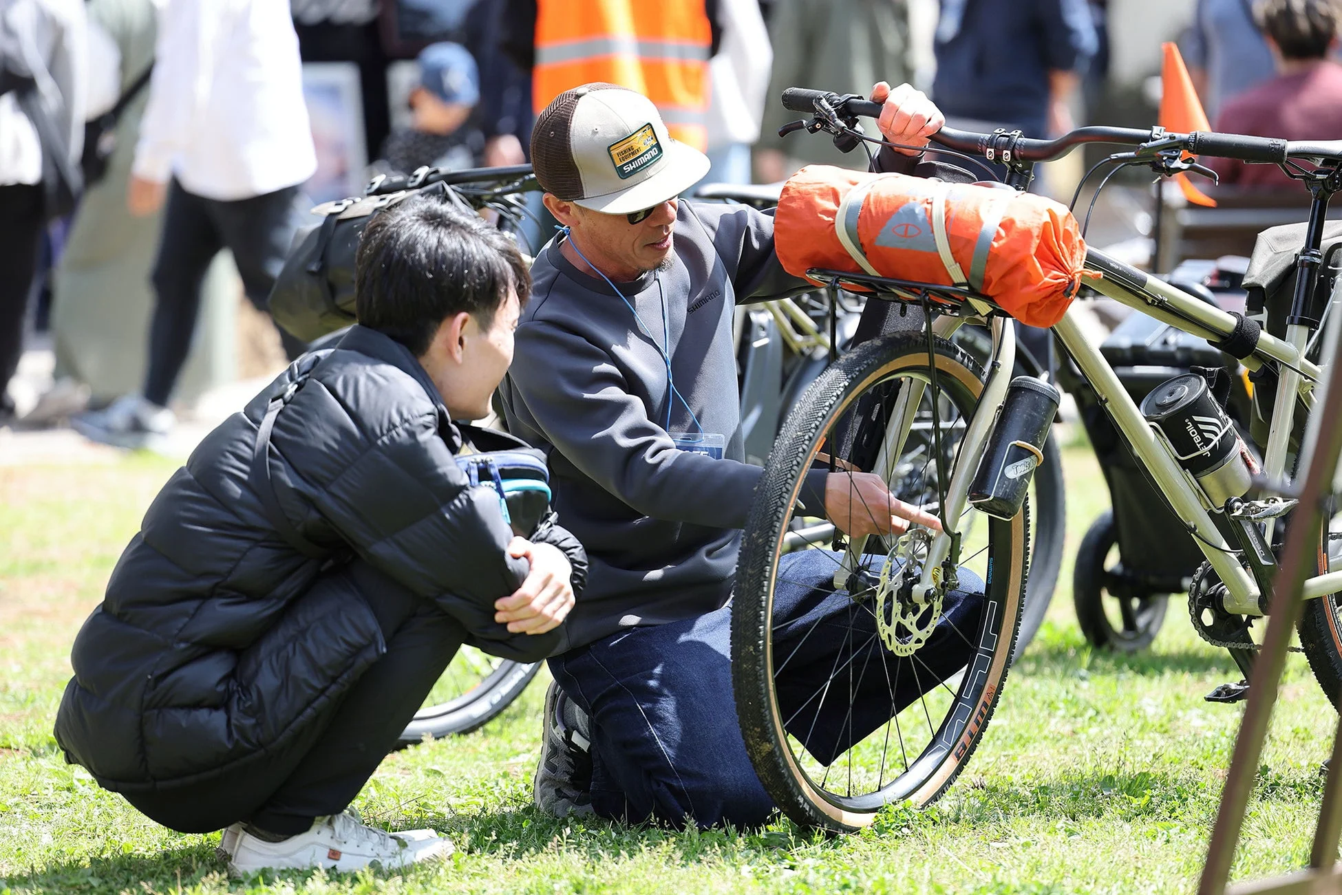 屋外イベントで、男性が自転車のホイール部分について説明している様子