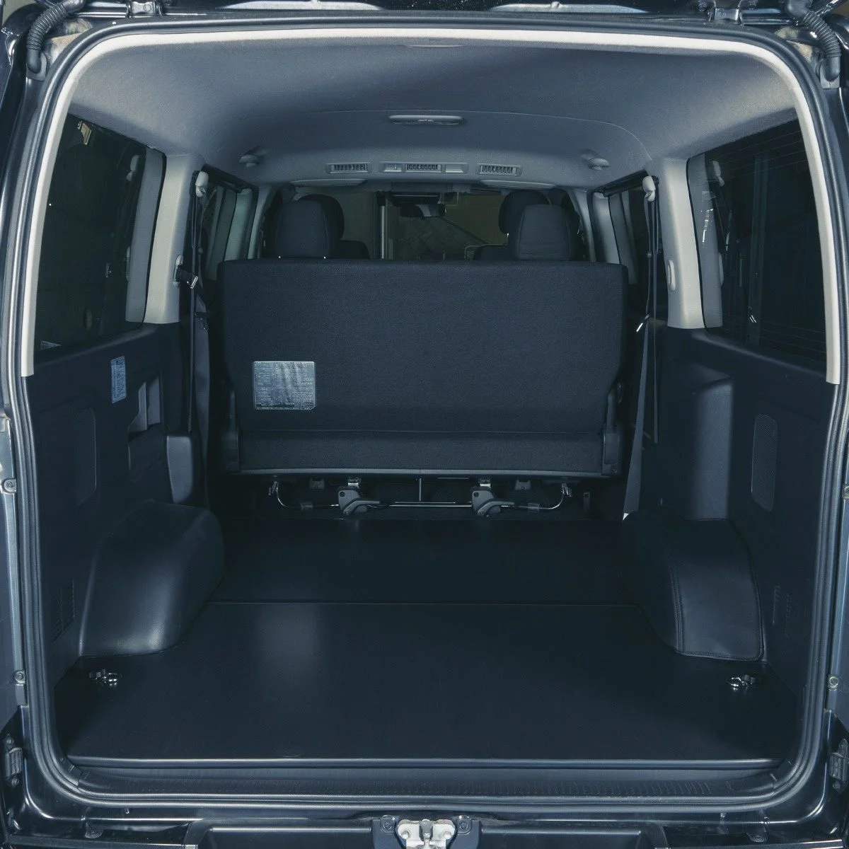 後部ドアが開いた状態のバンや商用車の車内が写っています。