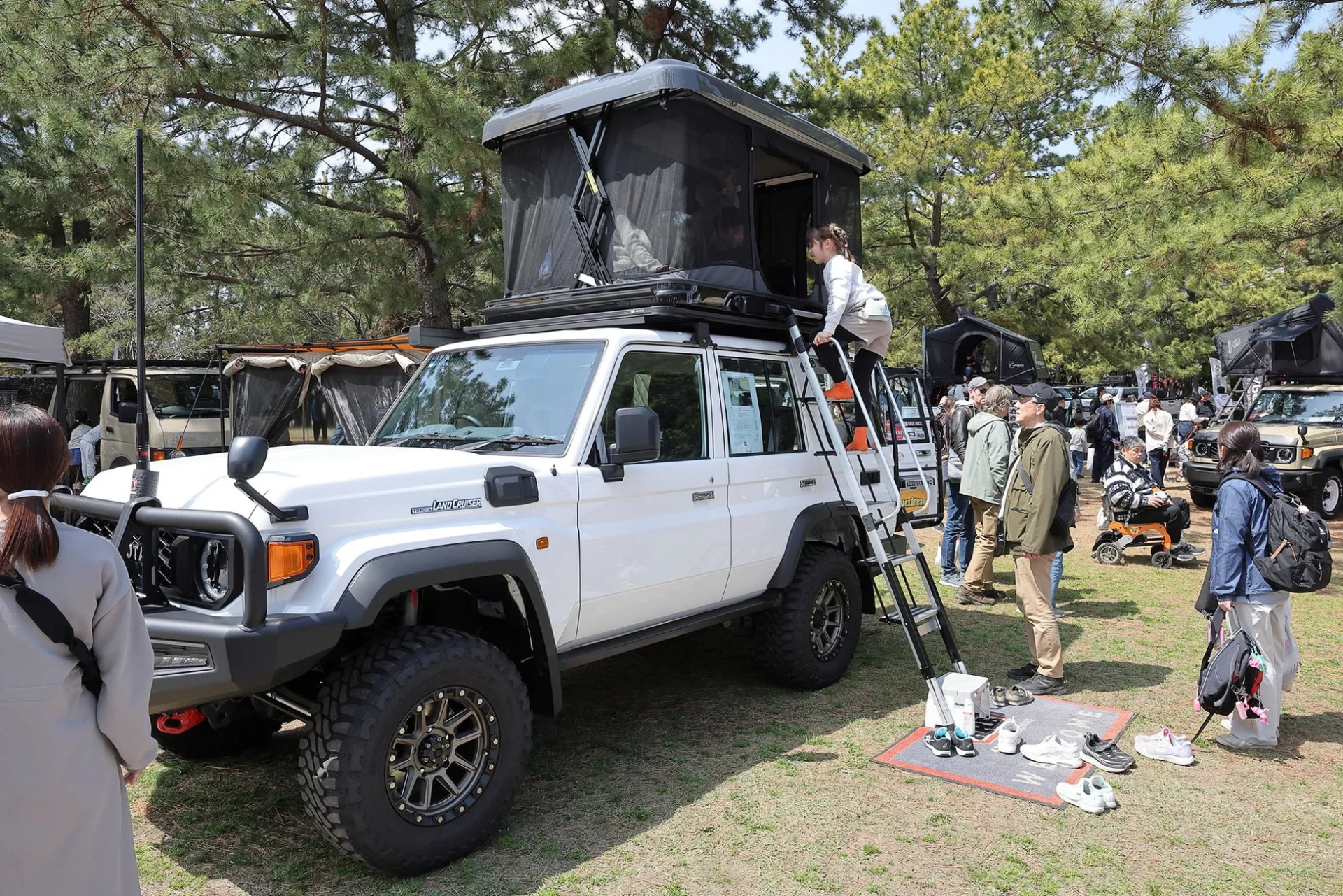 トヨタランドクルーザーにルーフトップテントが設置され、子供がはしごを登っている様子