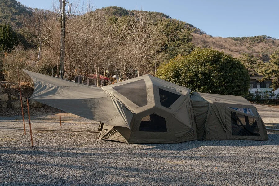 砂利の広場に設営された大型のカーキ色のテントとタープ