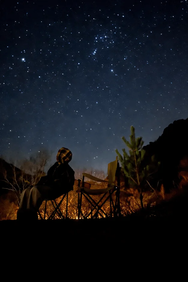 星空の下、焚き火を楽しむ人