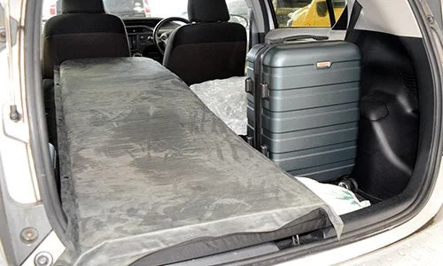 車のトランクに折り畳まれたマットレスとスーツケース