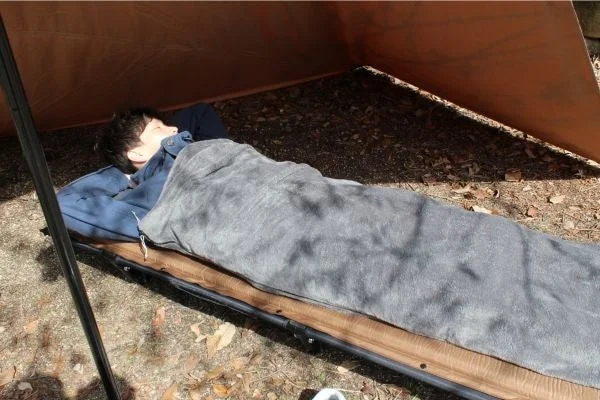 屋外でコットに寝る人