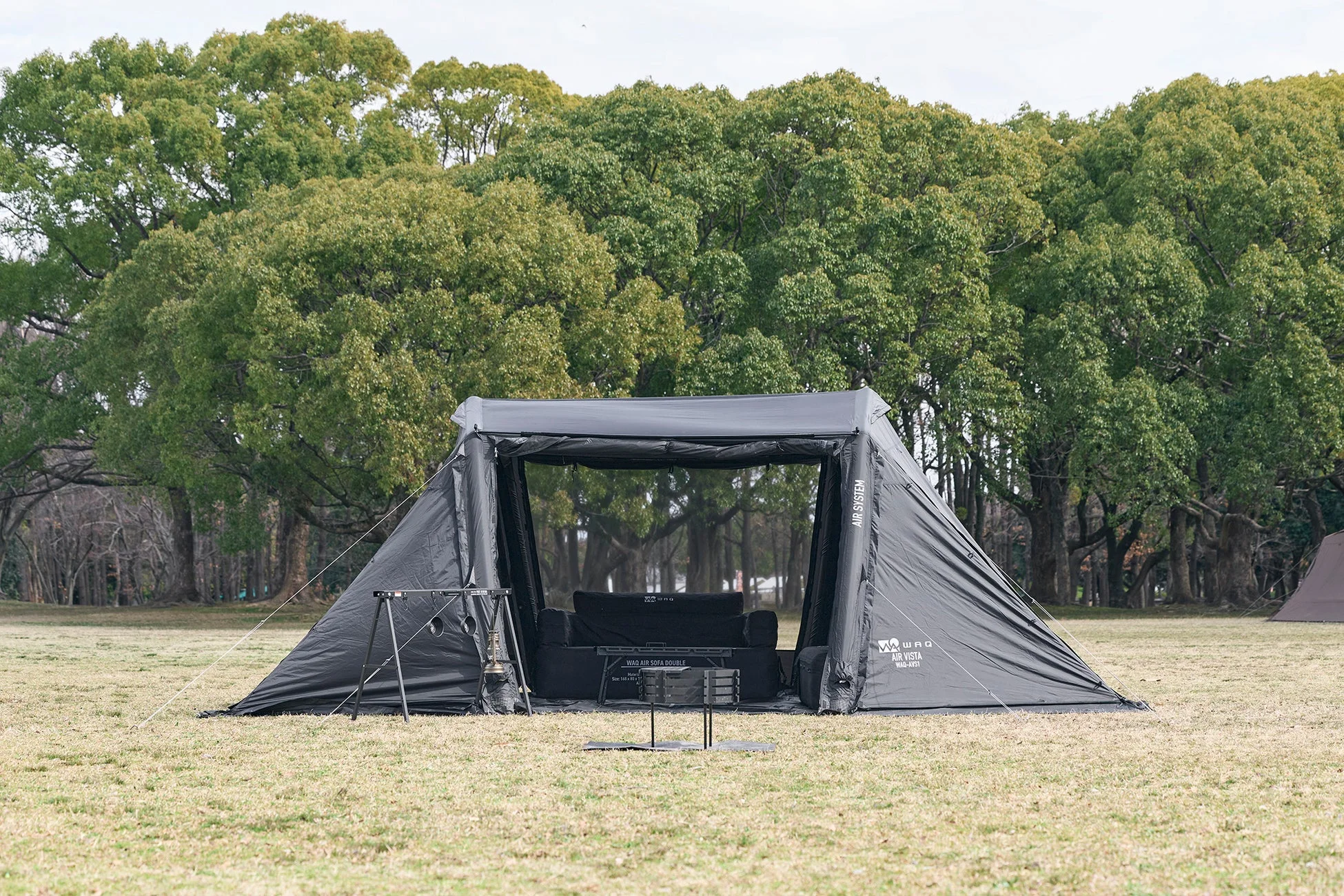 広々とした黒いエアテント（WAQ AIR VISTA）が芝生の上に設営されている様子