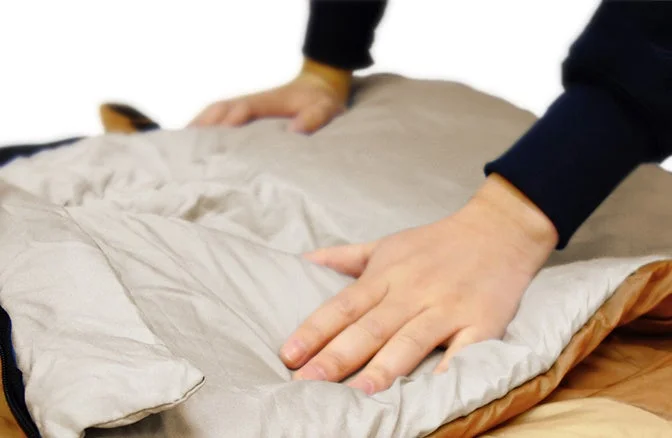 寝袋を整える人の手