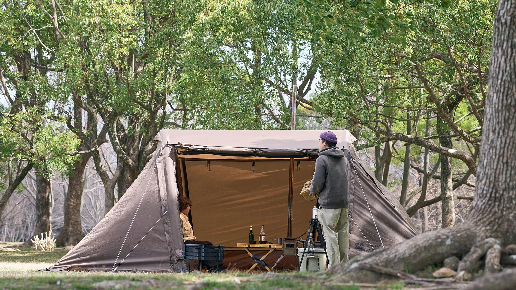 豊かな自然の中で、カップルがテントを設営し、リラックスしてキャンプを楽しんでいる様子