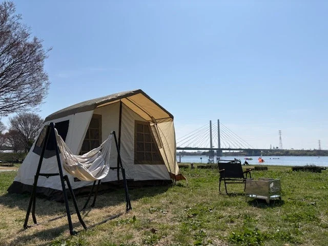 キャンプとハンモックが設置された川辺の風景