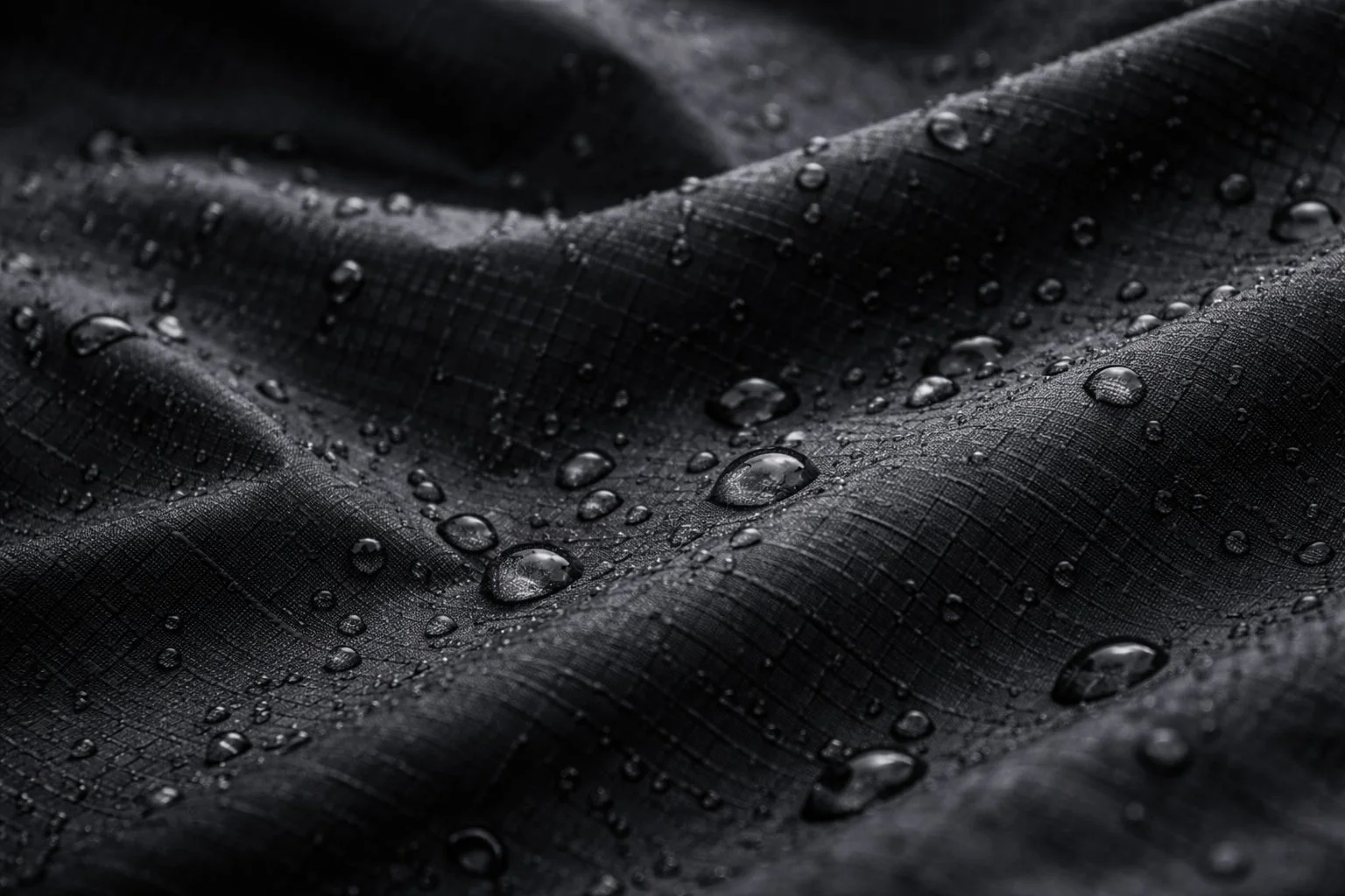 撥水加工された黒い生地の表面に水滴