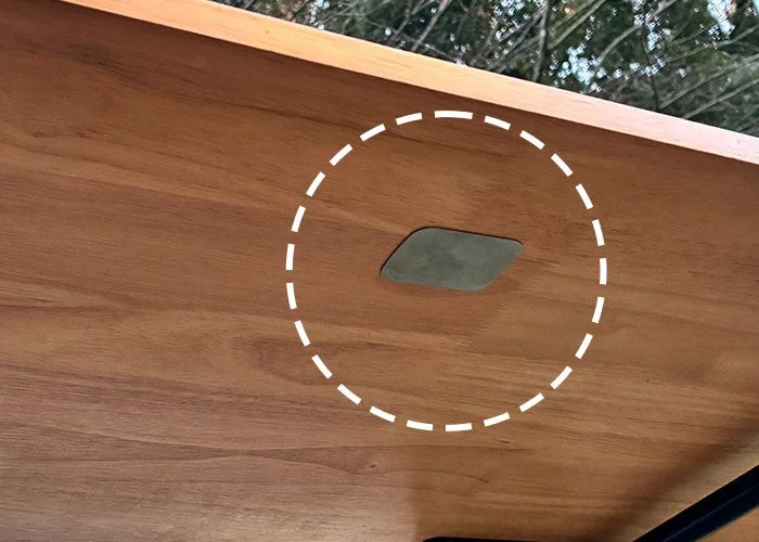 木目の美しい木製テーブルの裏面に、何らかの部品が取り付けられている様子