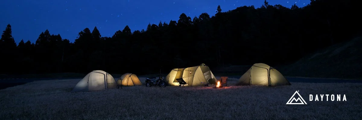 星空の下、複数のテントが並び、焚き火が燃える夜のキャンプ風景
