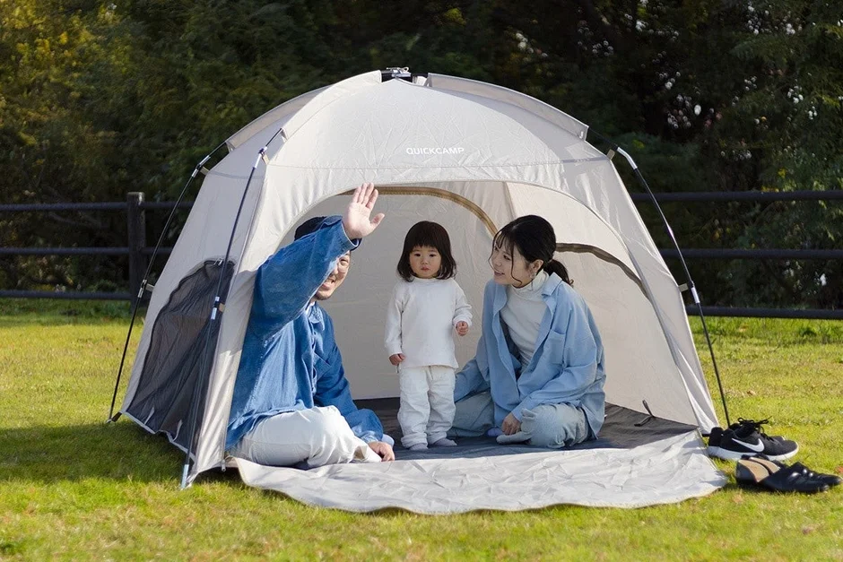 芝生の上でテントを張って楽しむ家族の姿