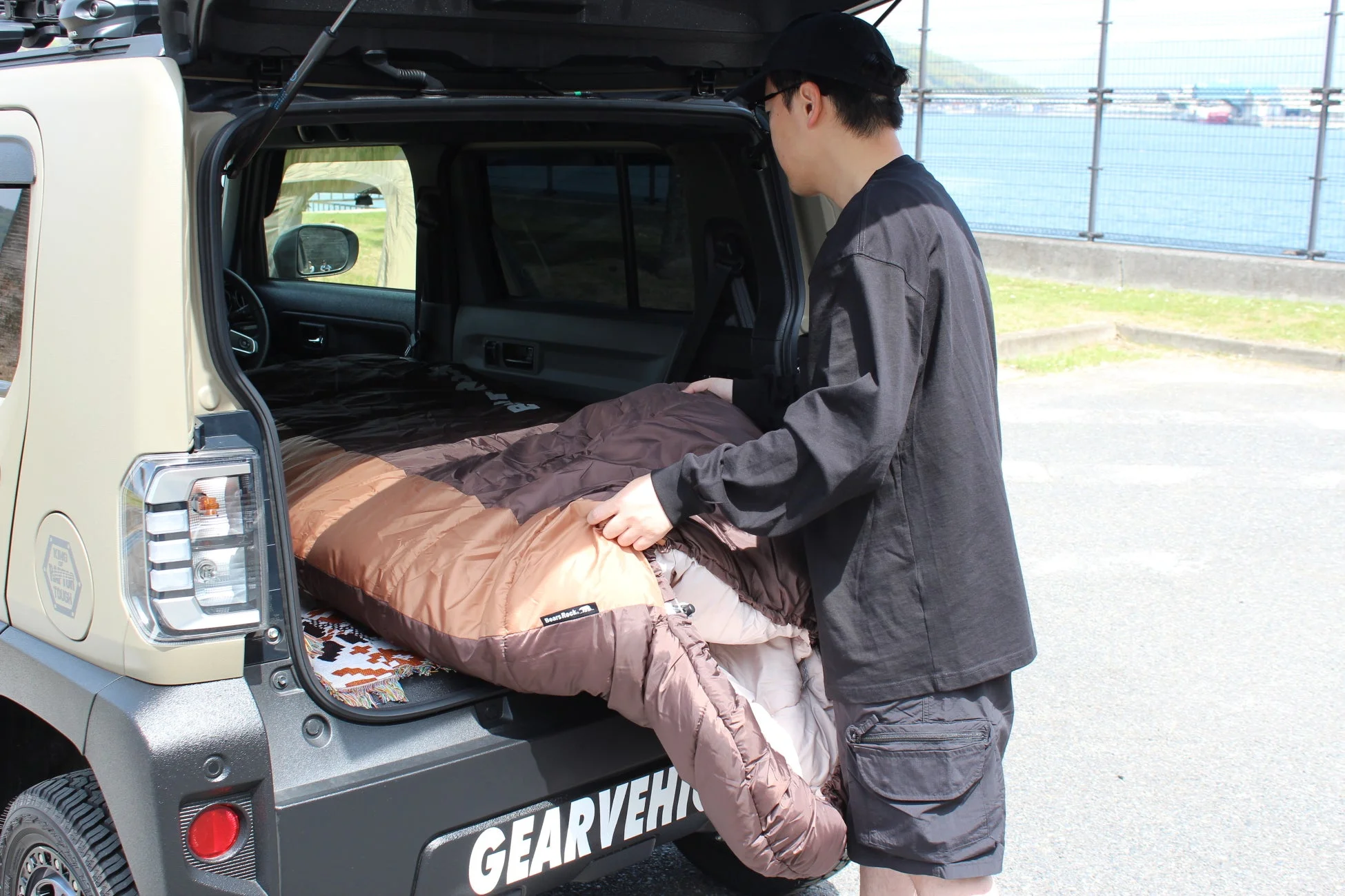 男性が車のトランクで寝袋を広げて荷物を整理