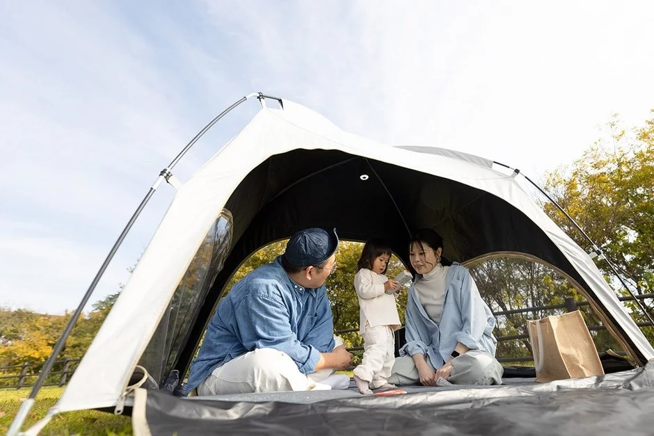 天気の良い日に家族3人がテントの中でくつろいでいる様子
