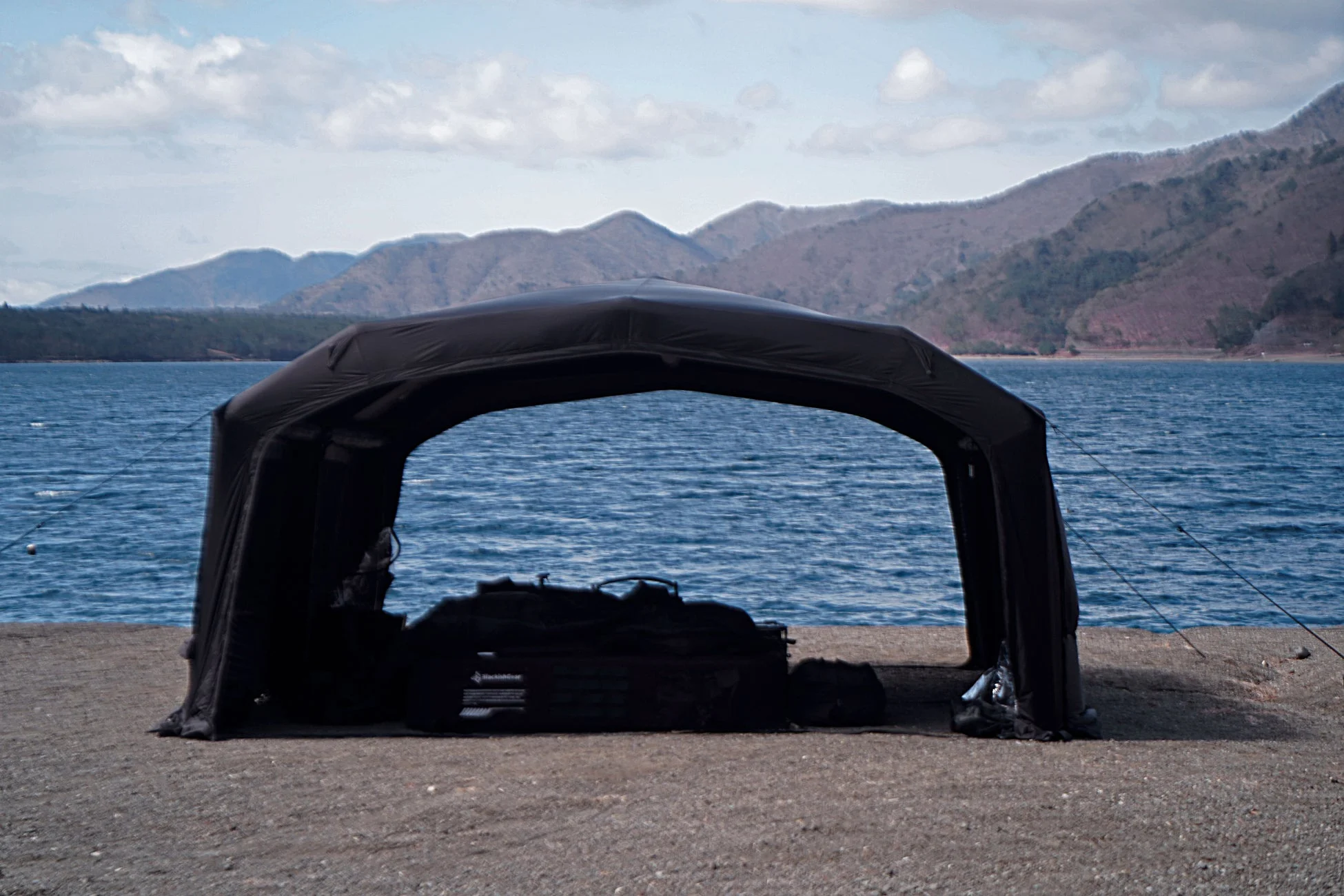 湖畔に設置された黒いシェルターと釣り道具