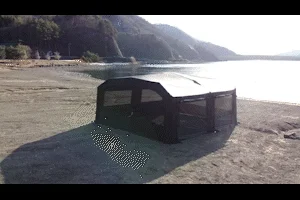 湖畔の広々とした砂浜に設置された黒い大型テント