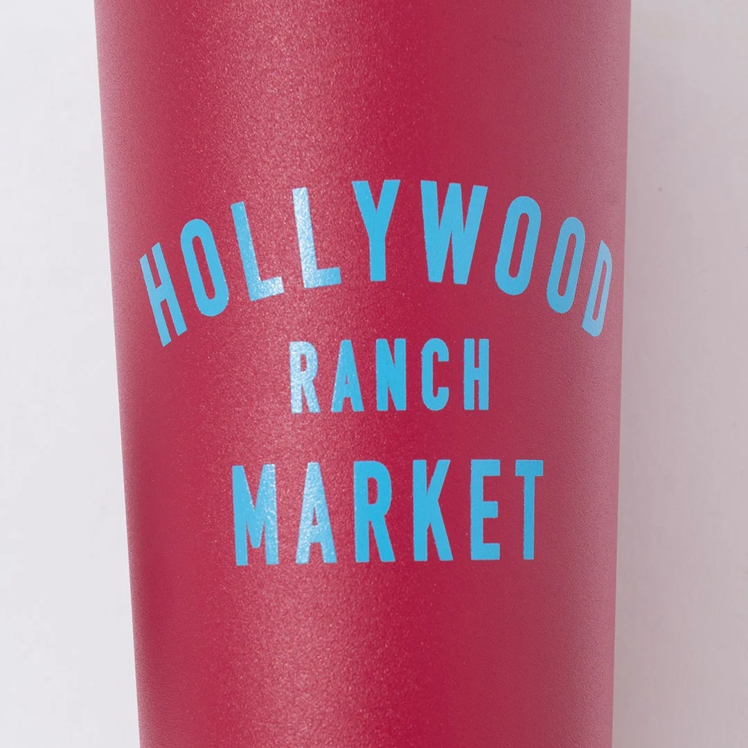 赤いタンブラーに「HOLLYWOOD RANCH MARKET」のロゴが水色でデザインされているクローズアップ画像です。