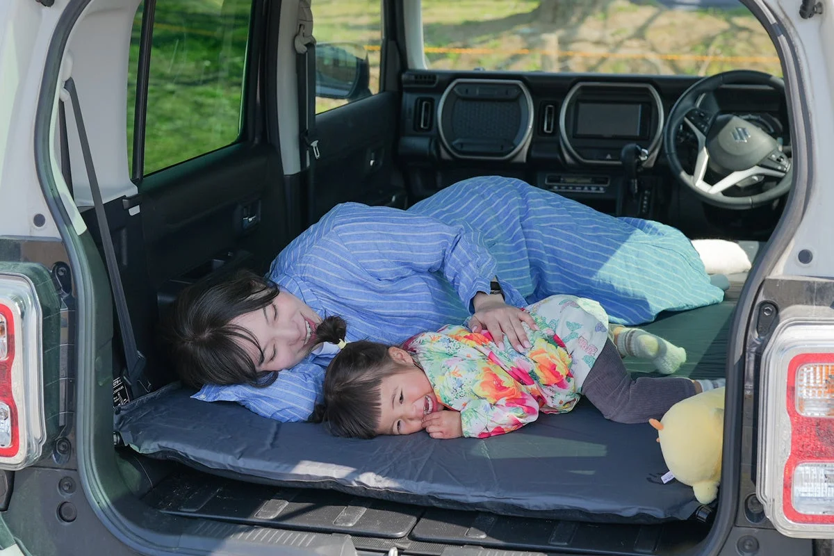車内でマットに横たわる親子