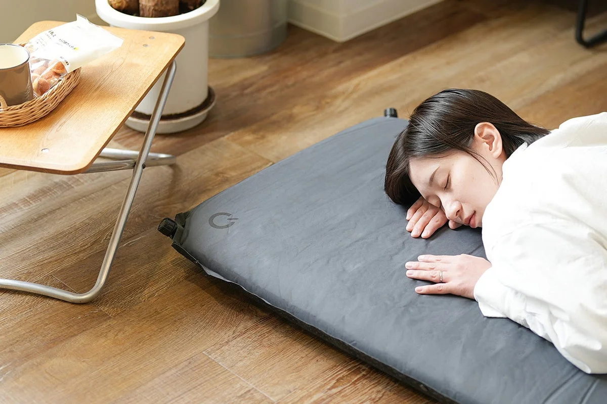 女性が木製フローリングでマットに横たわり仮眠している