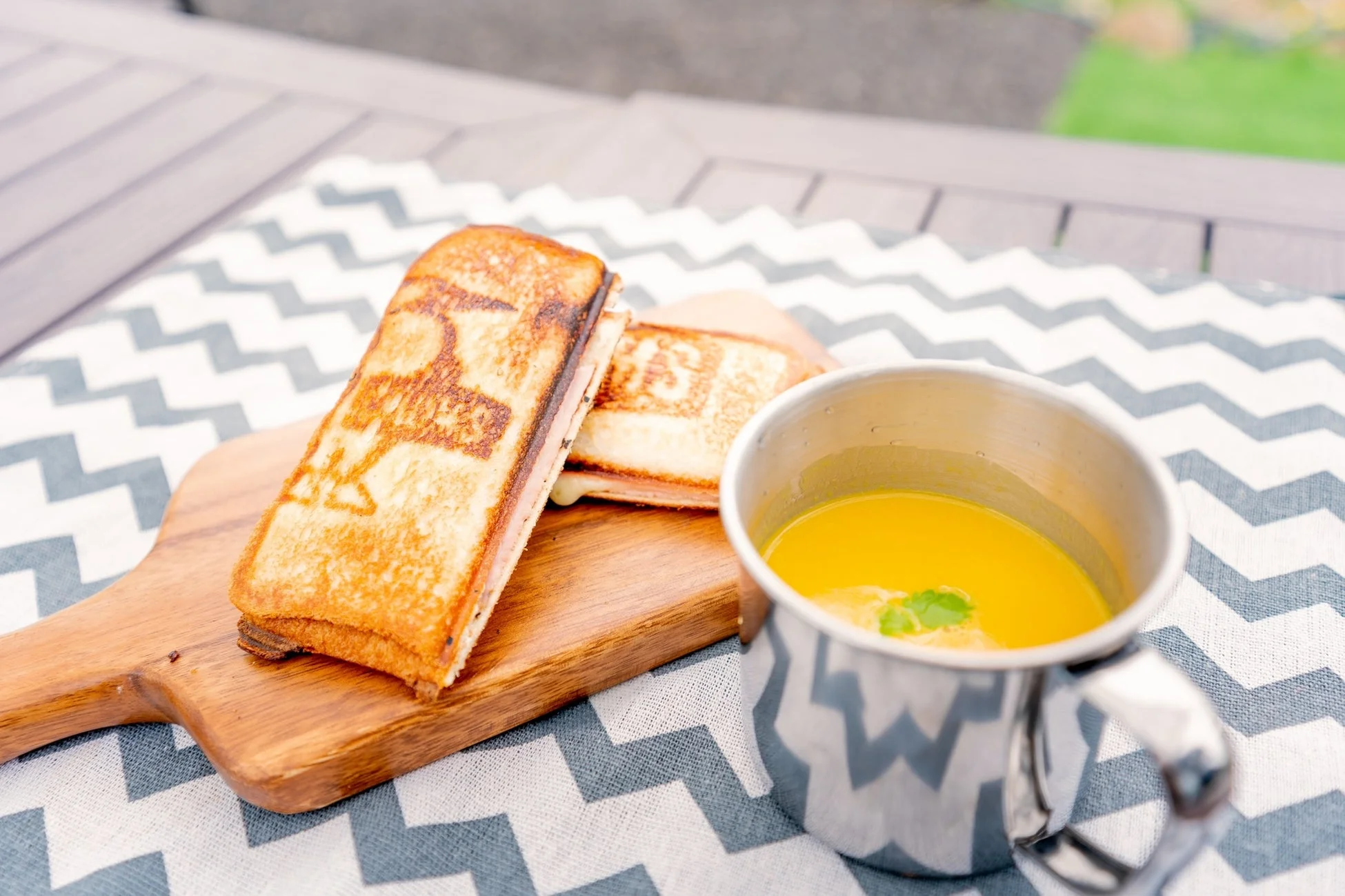 木製ボードに乗った焼き立てのホットサンドと、温かい黄色いスープが並べられた食事の風景