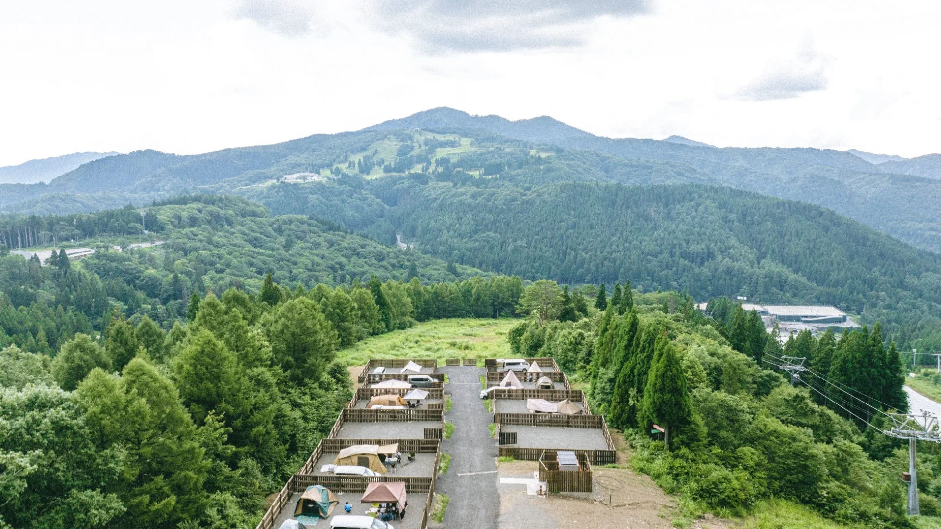 山間部の森林に囲まれたキャンプ場を上空から捉えた写真