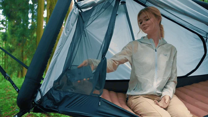 テントの中でスマートフォンを取り出そうとする女性