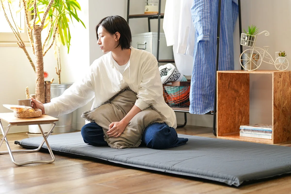 マットに座りコーヒーを飲む女性