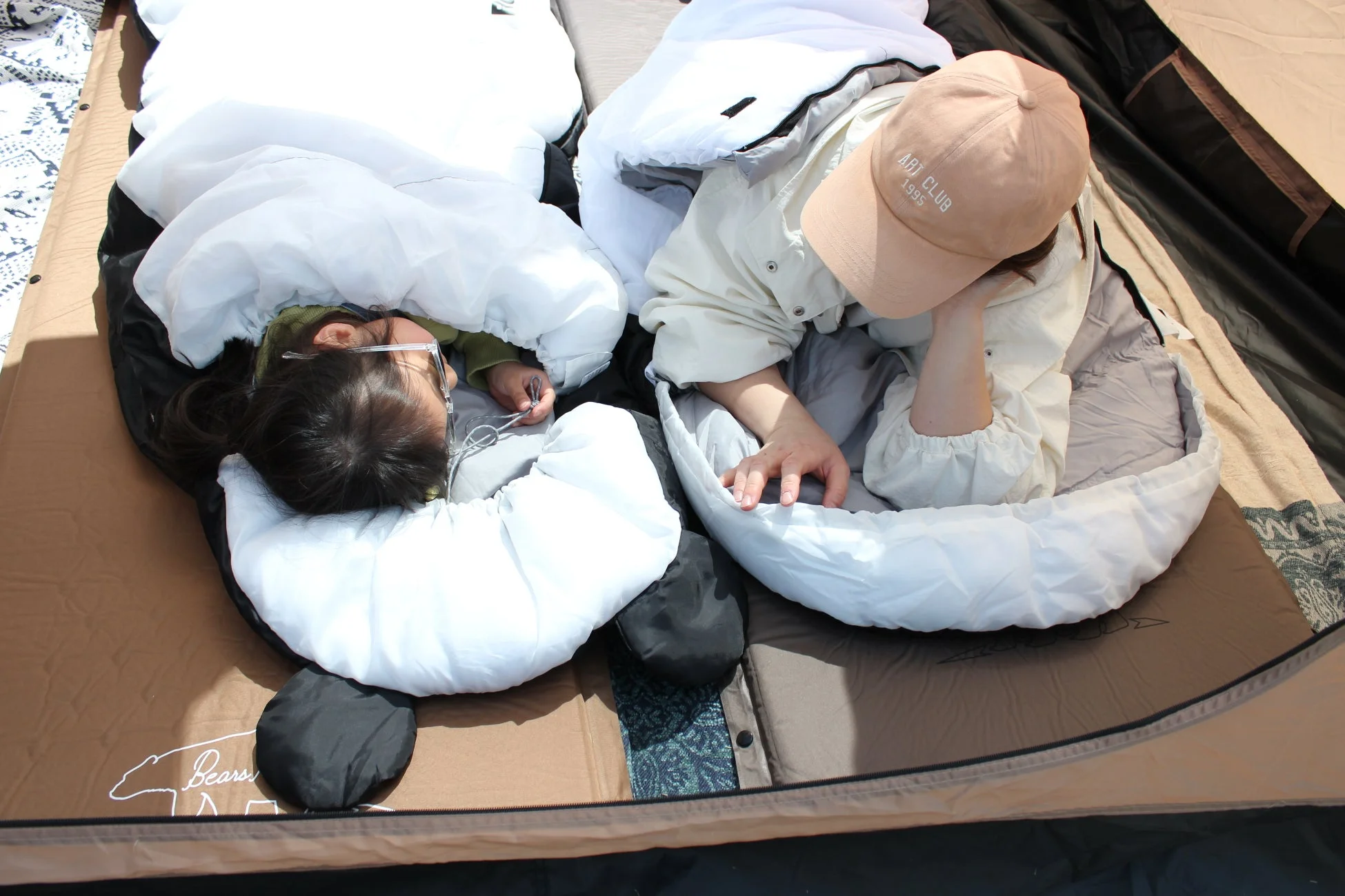 テントの中で寝袋にくるまってくつろぐ二人