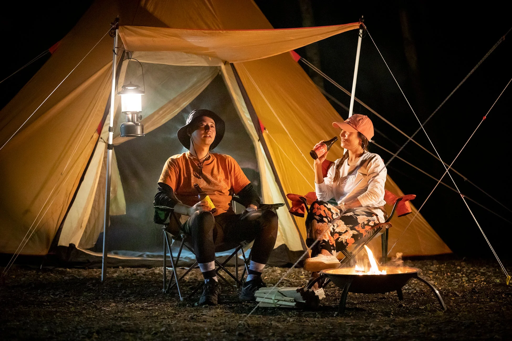 夜のキャンプ場で焚き火を囲む人々