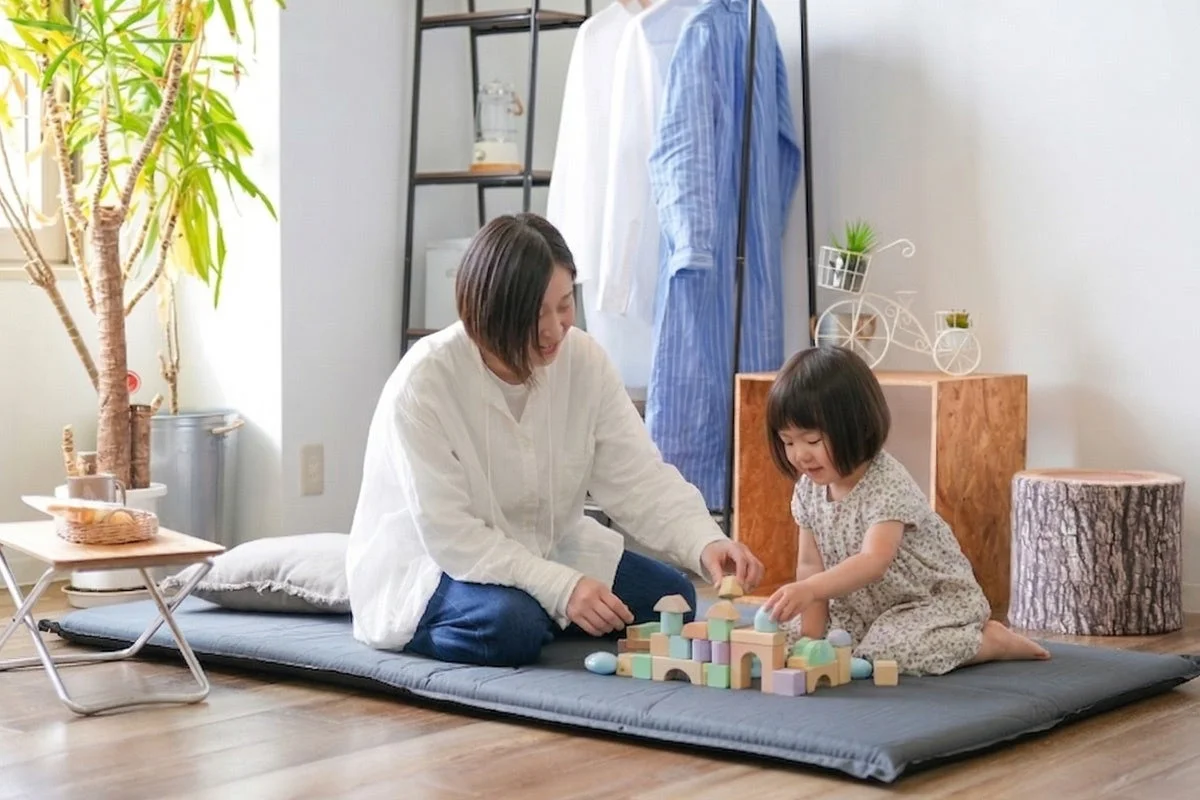 室内で親子がマットの上で積み木遊び
