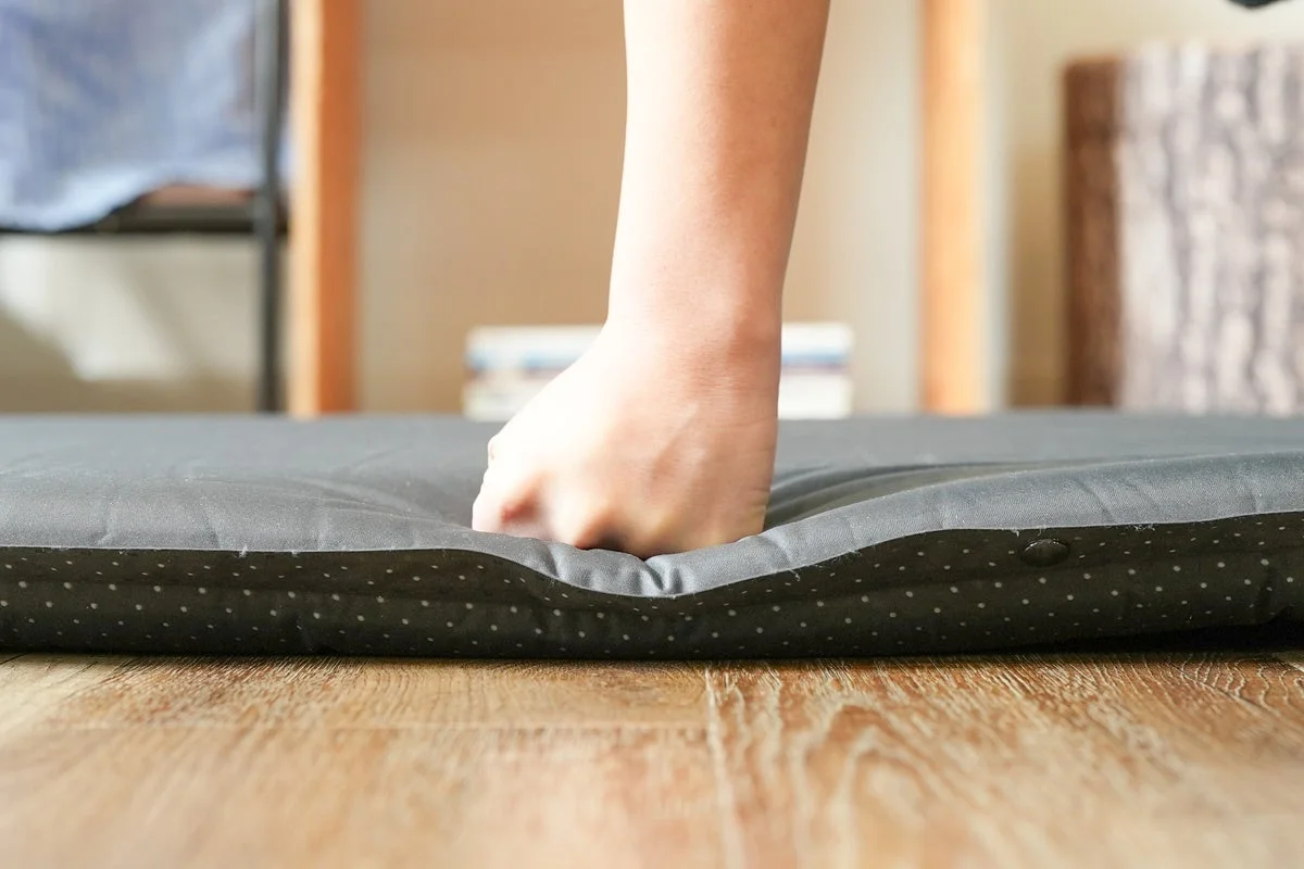 手がマットレスを押して柔らかさを確認する