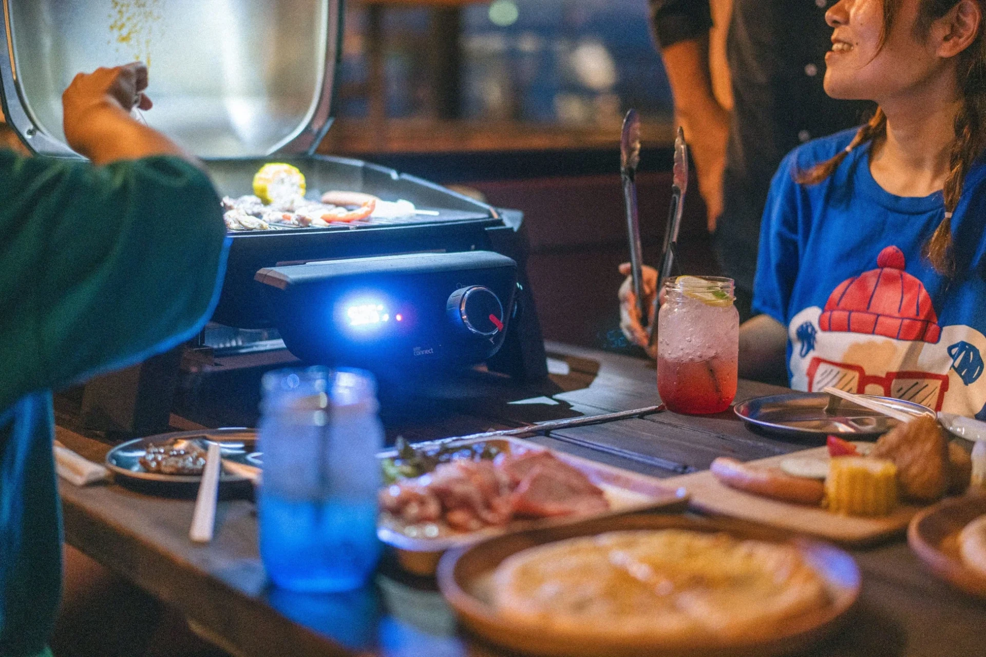 人々が電気グリルを囲んでバーベキューを楽しんでいる様子