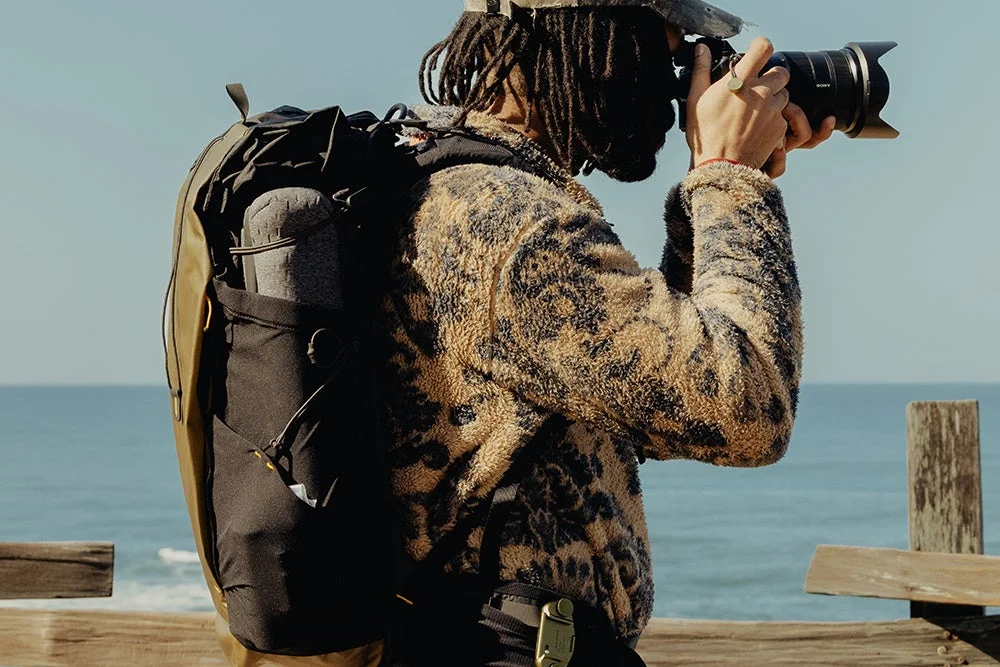 カメラを構える人物とバックパックの画像
