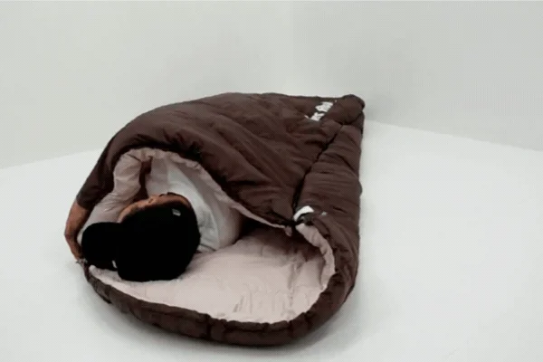白い部屋で茶色の寝袋に入って休んでいる人物