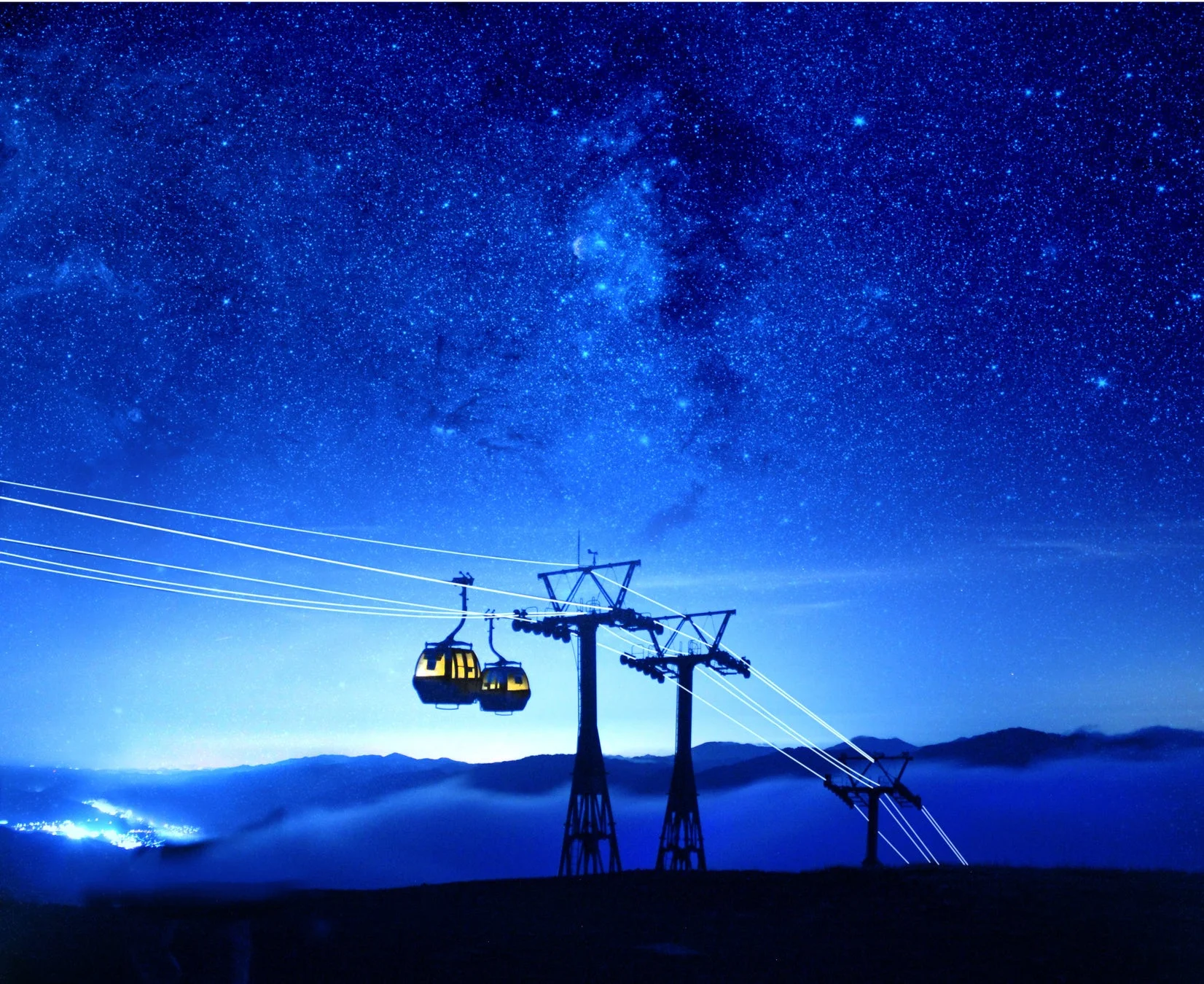満天の星空の下、夜の山間をロープウェイのゴンドラが静かに進む幻想的な風景