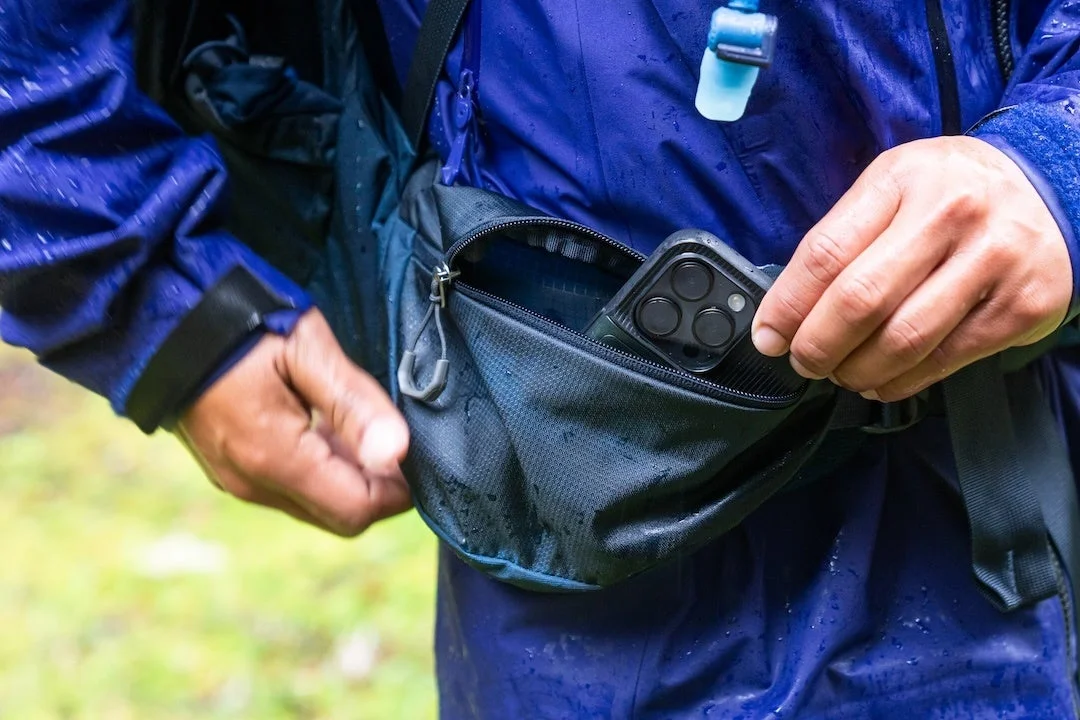 バックパックのポケットからスマートフォンを取り出す手元