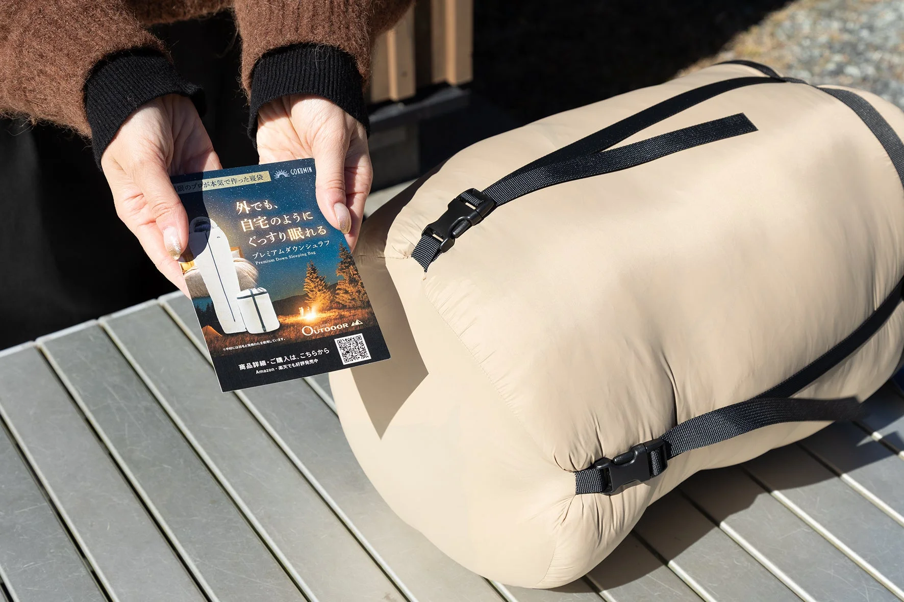 GOKUMINプレミアムダウンシュラフの広告カードを持つ女性
