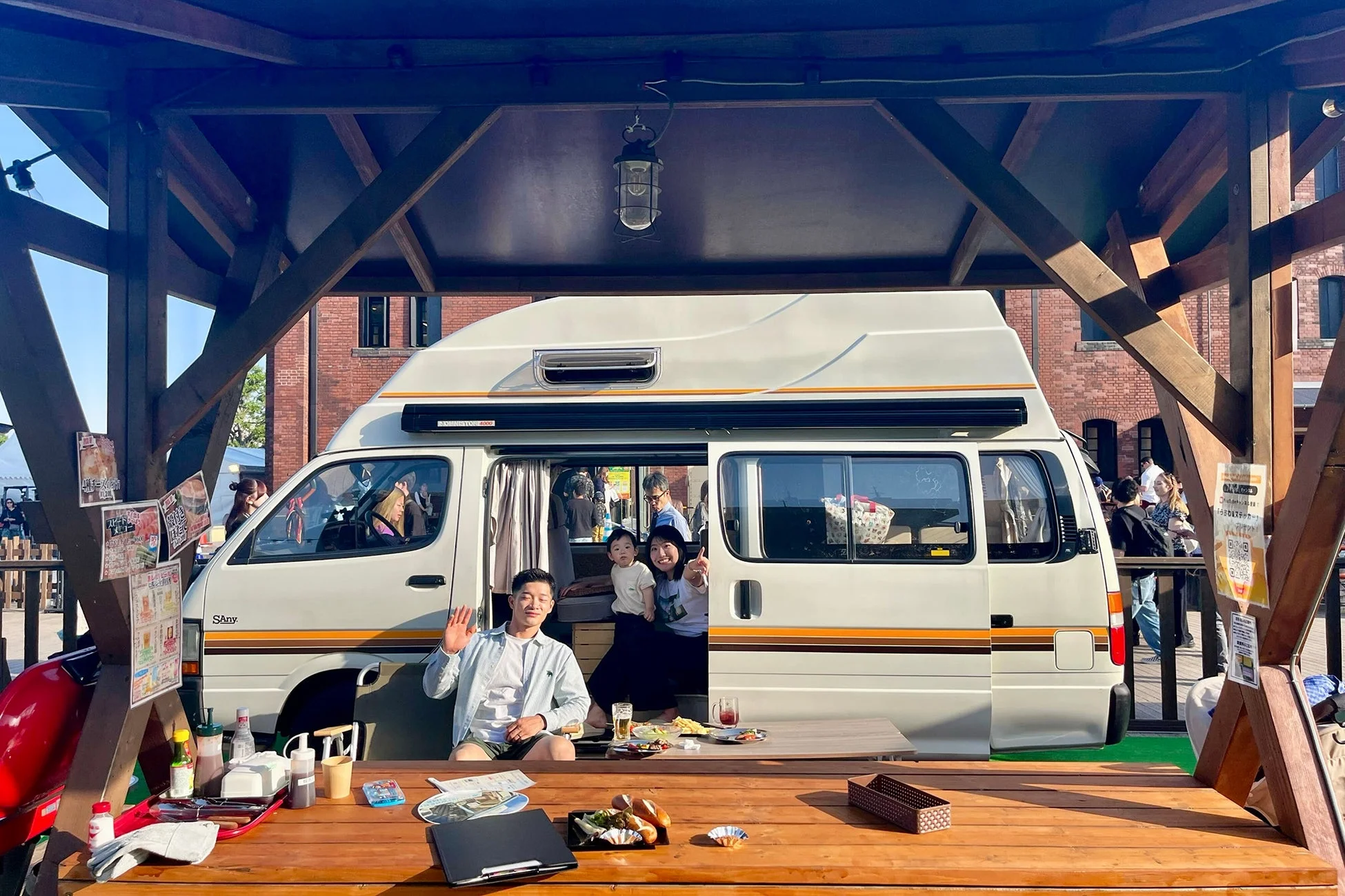 キャンピングカーの横で食事を楽しむ家族