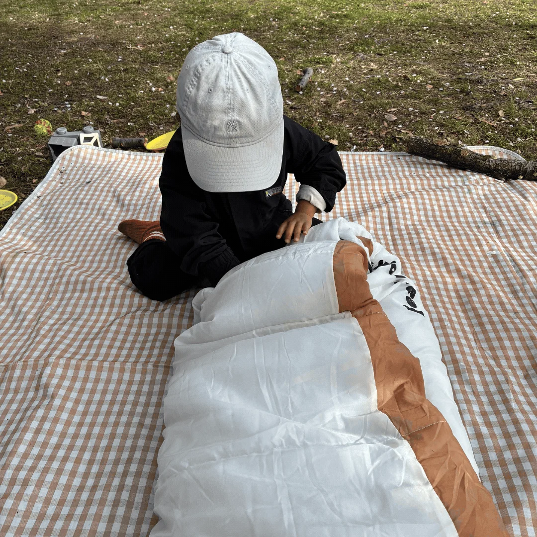 チェック柄のピクニックブランケットの上に座る子供