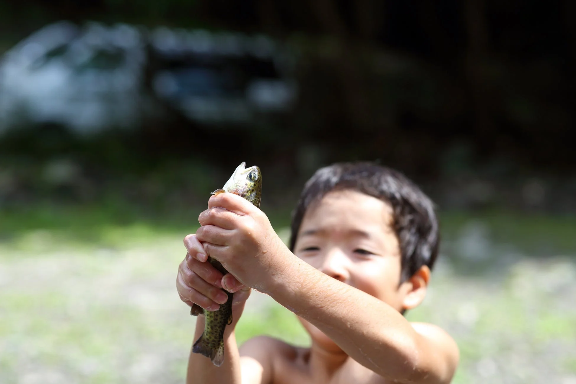 少年が捕まえた魚を両手で持ち上げている様子