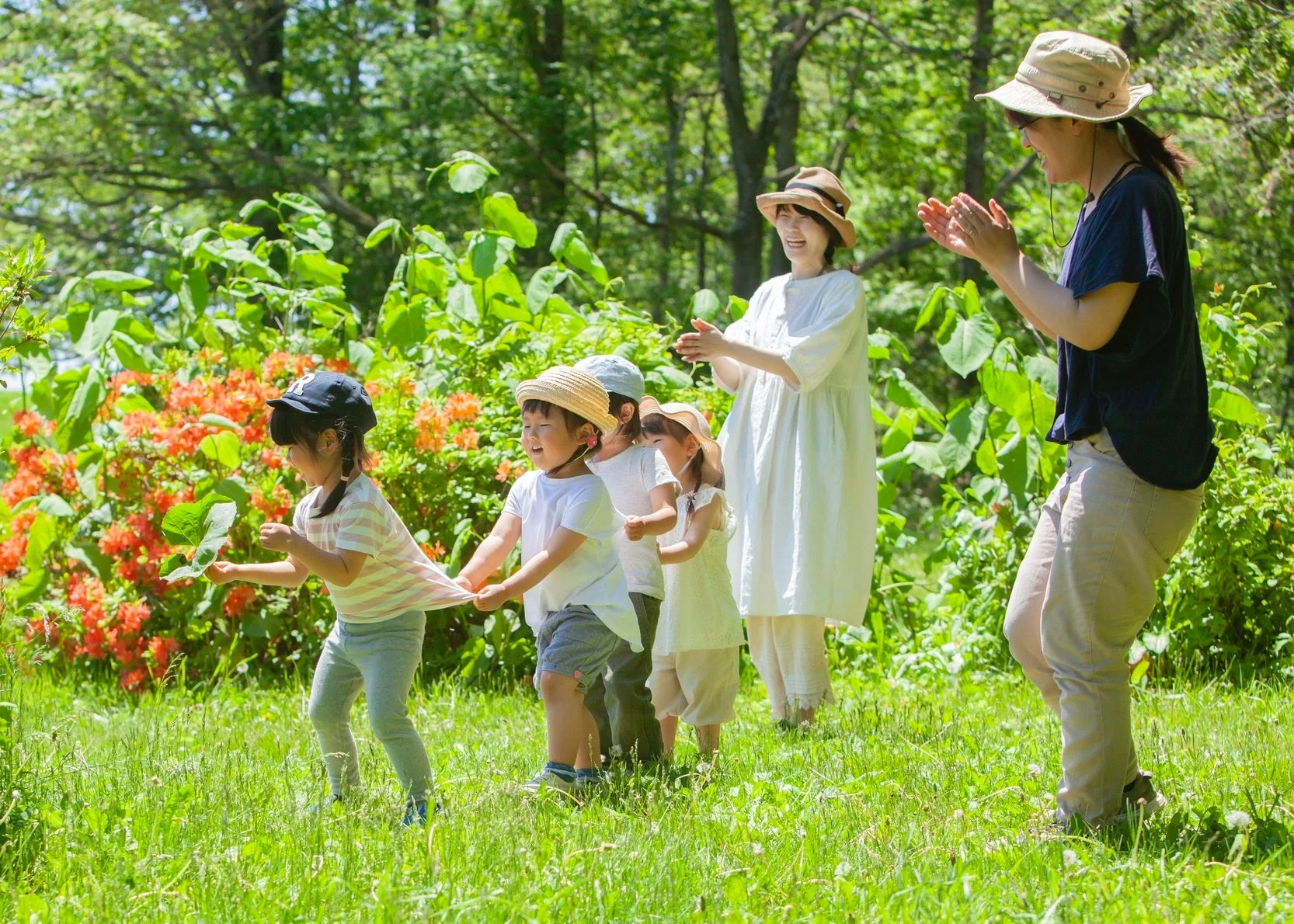 緑豊かな公園で数人の子供たちが大人たちと楽しそうに遊んでいる様子