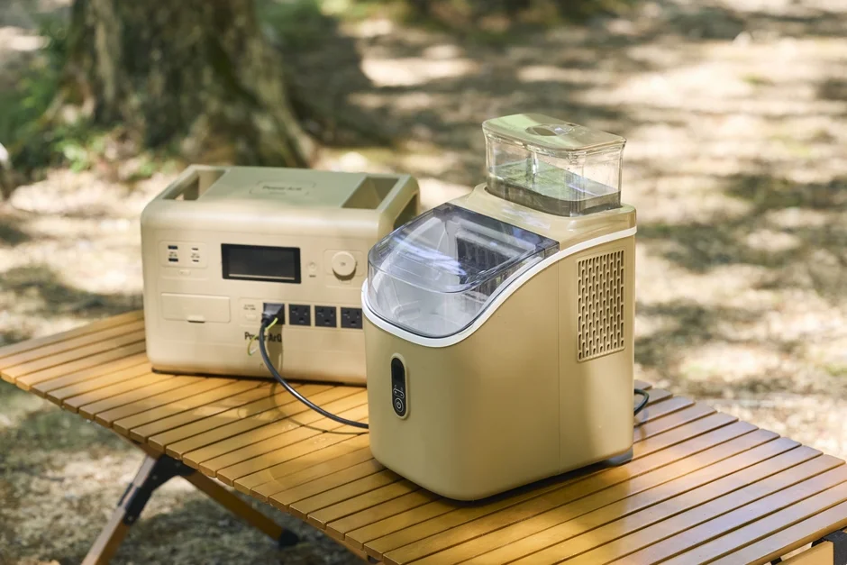 キャンプやアウトドアで使用できるポータブル電源と製氷機が木製のテーブルの上に置かれている様子