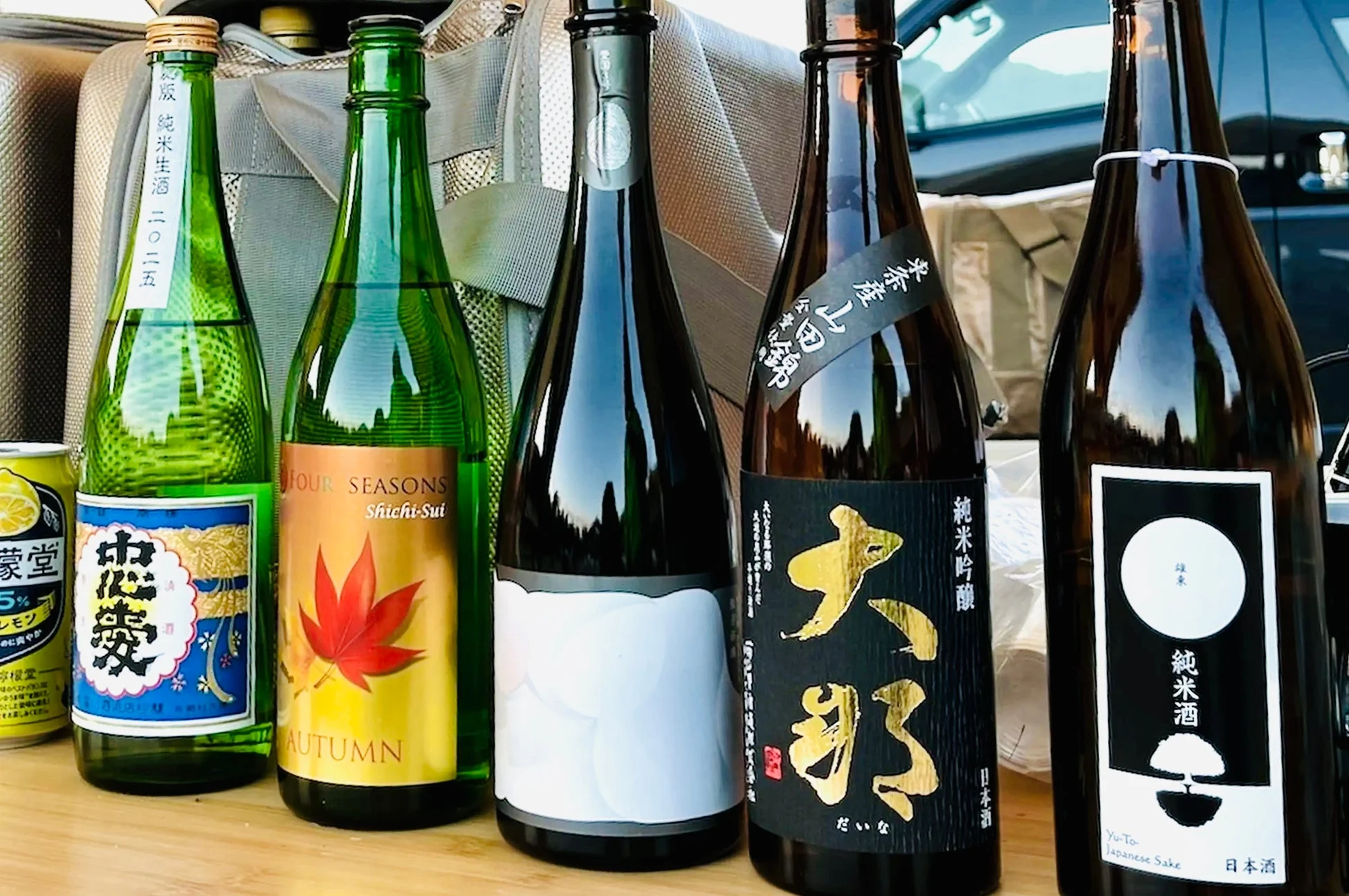 様々な種類の日本酒の瓶とレモンサワーの缶が並べられています