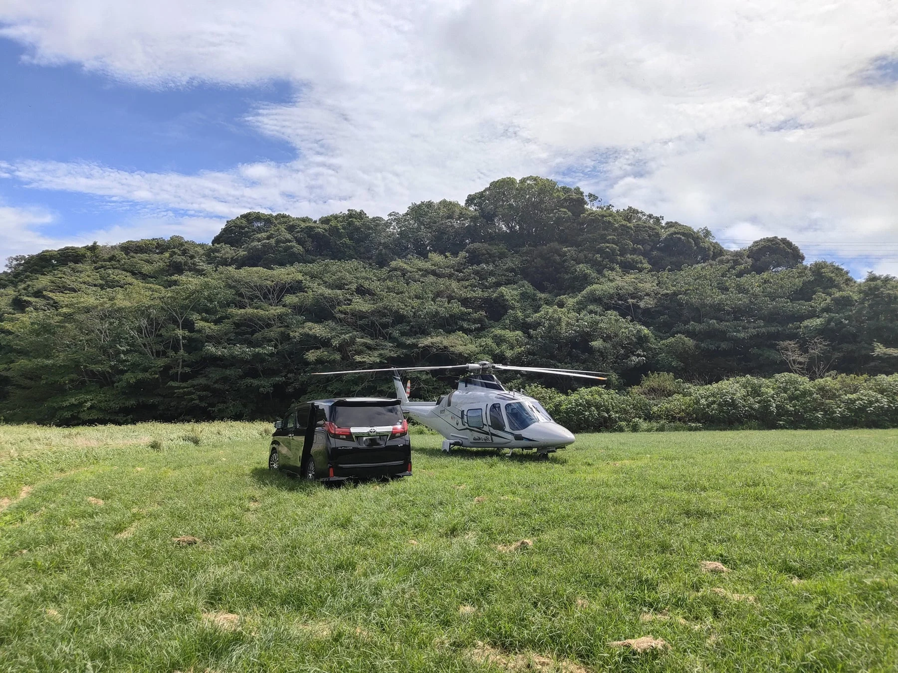 草原に駐機するヘリコプターとバン