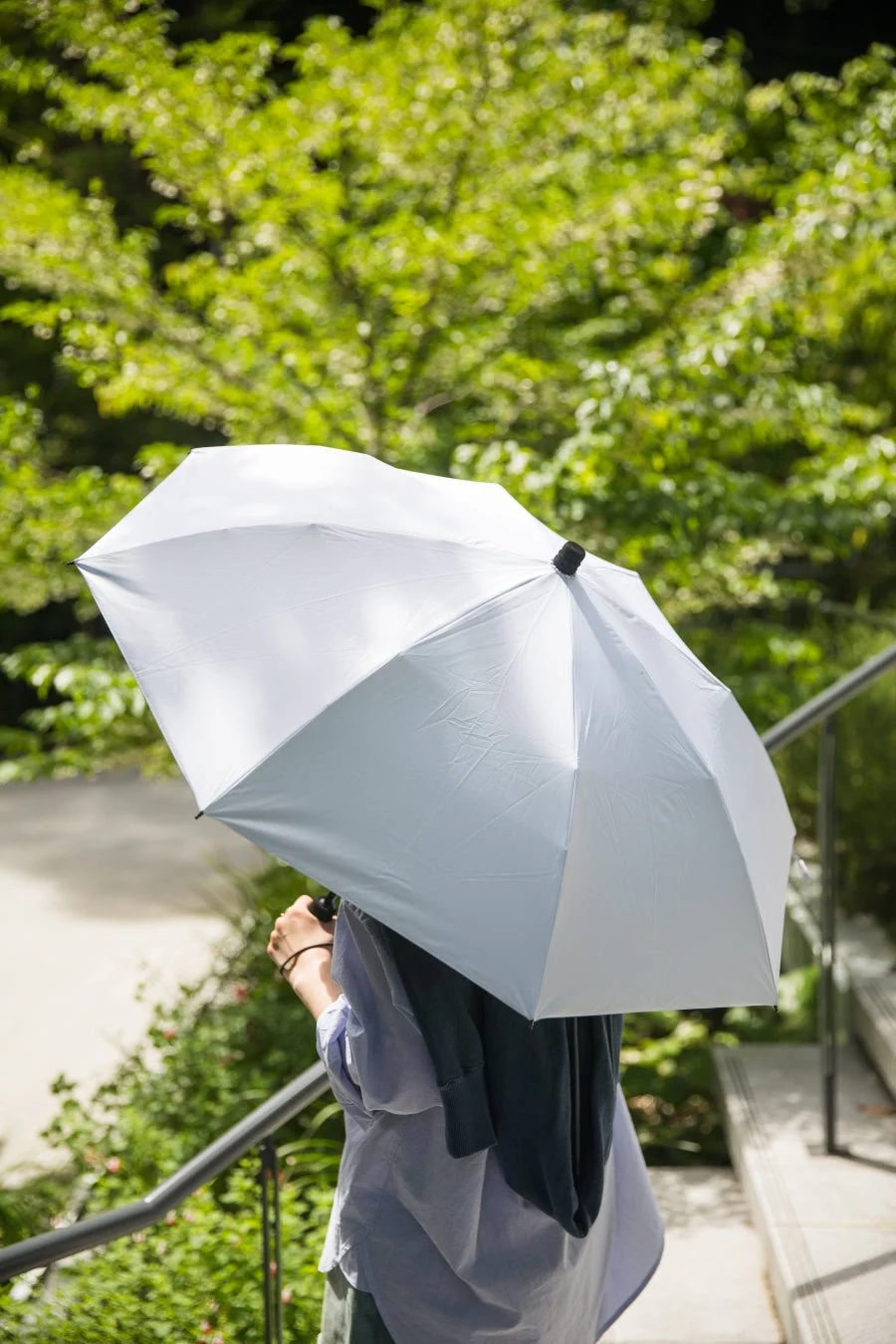 晴れた日に日傘を差して歩く人物
