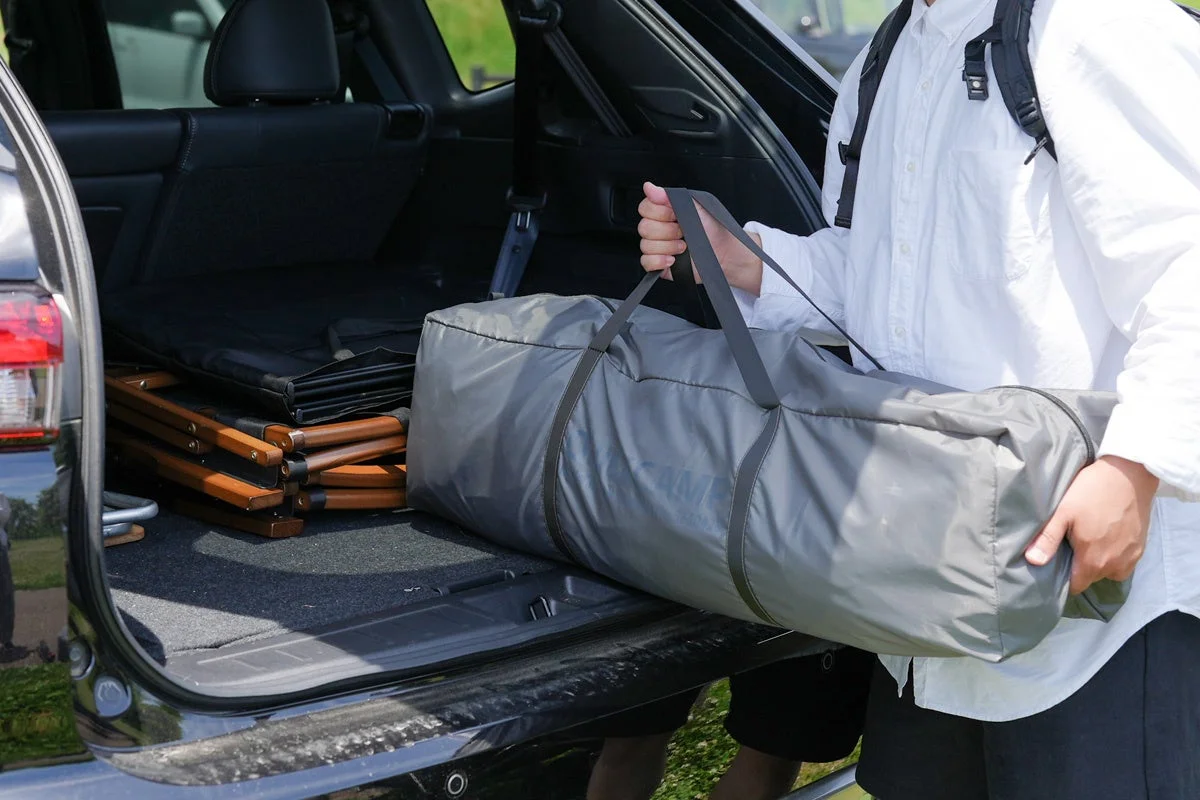 車のトランクにキャンプ用品を積み込んでいる様子です。