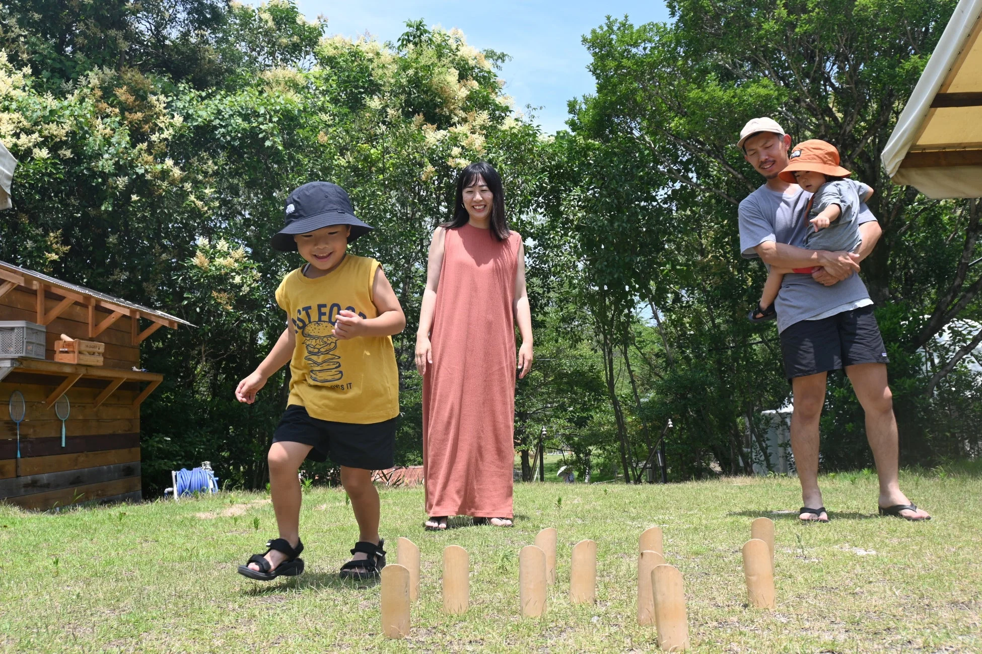 晴れた日の屋外で、家族が芝生の上で木製のピンを使ったゲームを楽しんでいます。