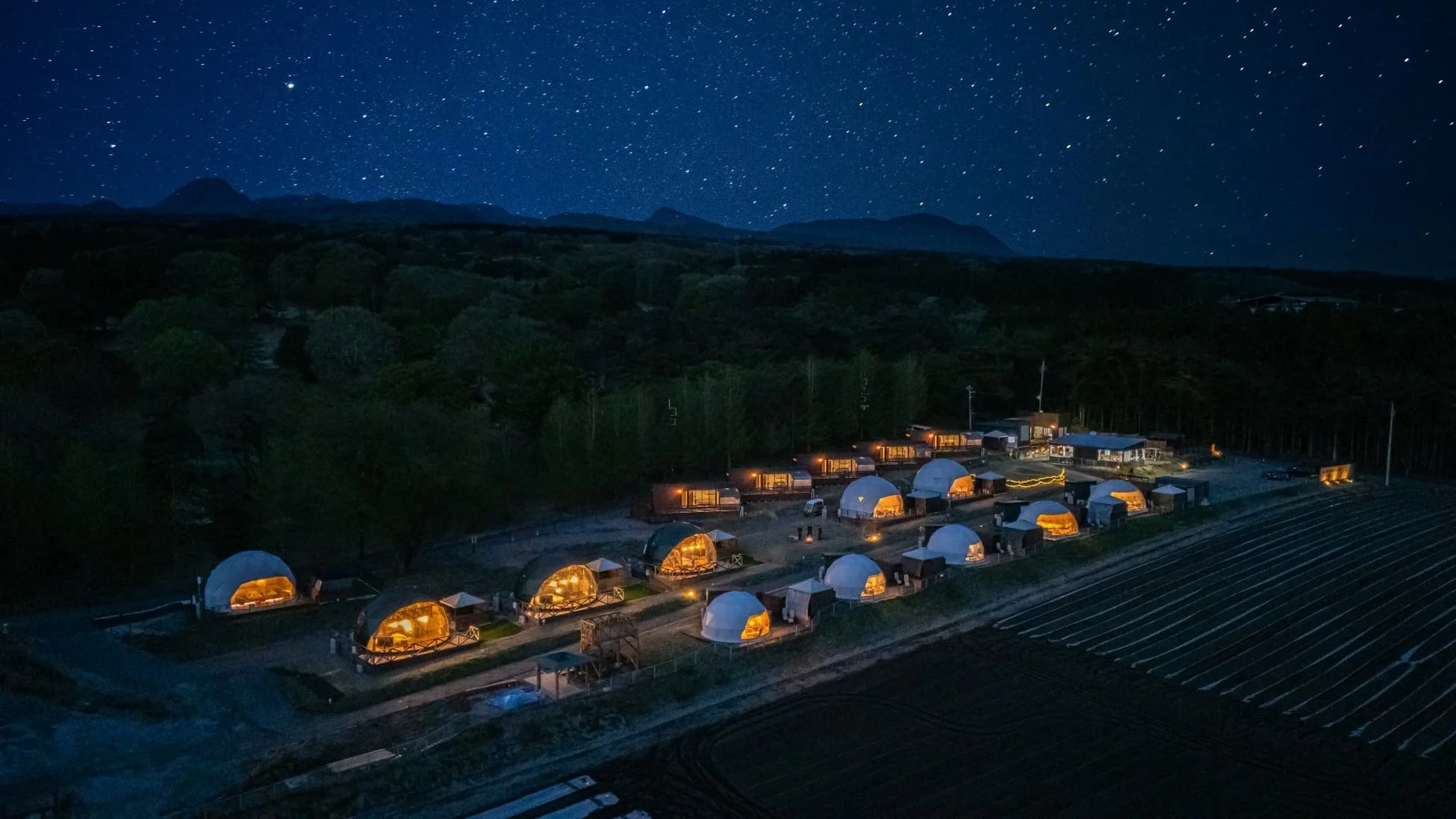 星空の下、山と森に囲まれたグランピング施設
