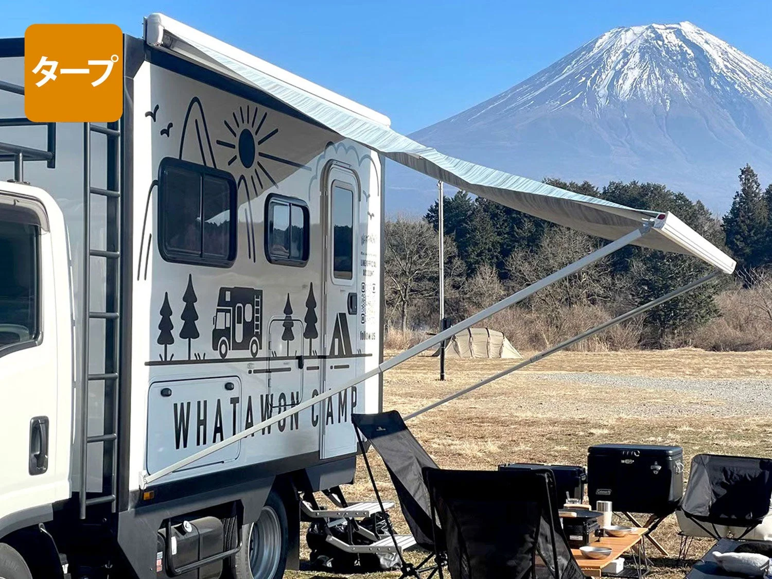 富士山を背景にオーニングを広げて駐車しているキャンピングカー